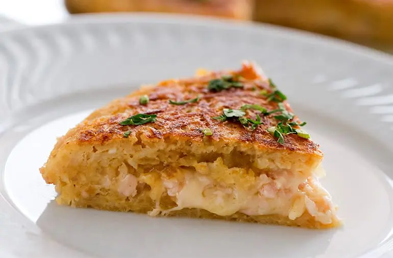 Fatia cremosa de batata suíça de batata palha feita com presunto e queijo, com salsinha para decorar