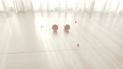 Dois copos de plástico no chão, cercados por bolinhas de papel amassado, em jogo de acertar o alvo