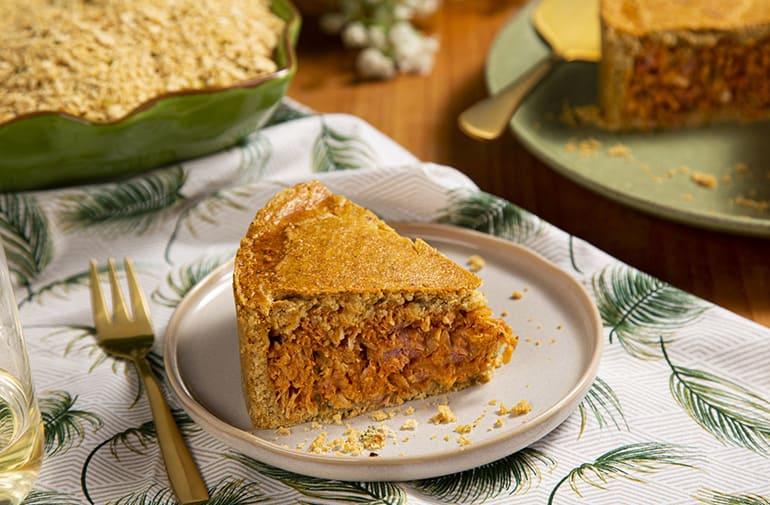 Fatia de torta de frango com farofa picante em mesa com decoração para almoço