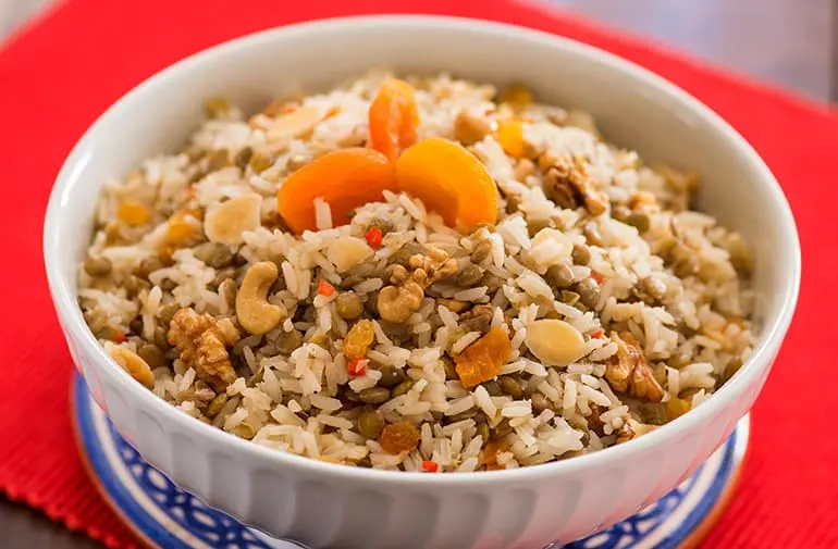 Arroz com lentilha e frutas secas em pequena forma de porcelana, decorado com damasco