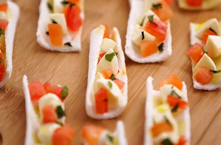 Receita de canapé feita com barquinhos de tapioca recheados com tomate, mussarela de búfala e manjericão