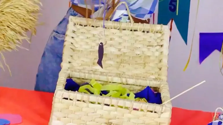 Caixa de palha com peixinhos de papel para brincadeira de pescaria e correio elegante em festa junina