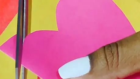 Papel colorido rosa é cortado em forma de coração, fazendo um cartão de correio elegante para festa junina