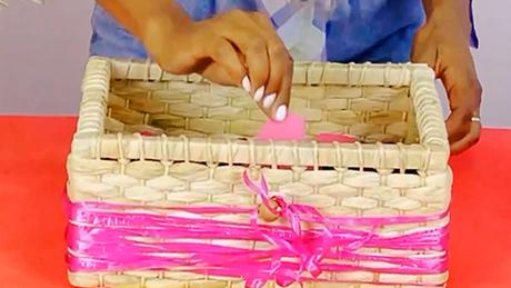 Um cartão em forma de coração é colocado em uma caixa de palha com fitas cor de rosa, para correio elegante