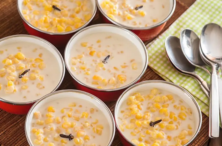 Panelinhas com canjica munguzá amarela, cremosa, decorada com cravo, servidas como sobremesa