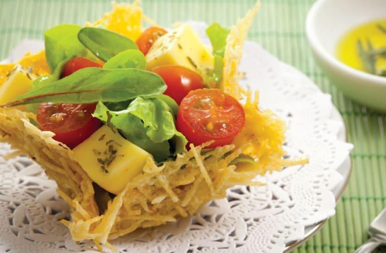 Cestinha comestível feita de parmesão e batata palha, com salada de folhas, tomate cereja e queijo, temperada com ervas