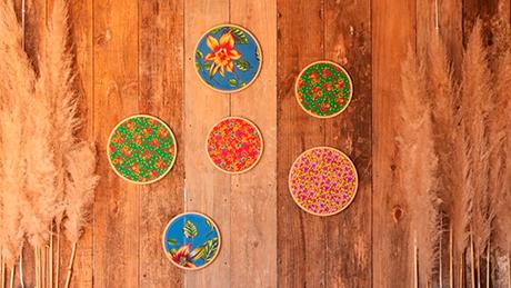 Quadros decorativos redondos feitos com tecidos típicos de festa junina e bastidores sobre parede rústica de madeira