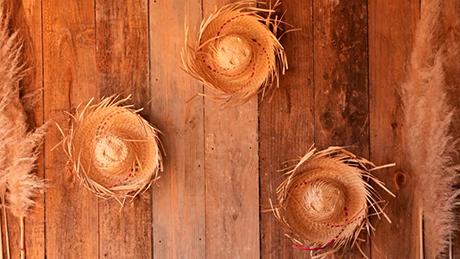 Chapéus de palha de festa junina estão colados como decoração artesanal em uma parede rústica de madeira