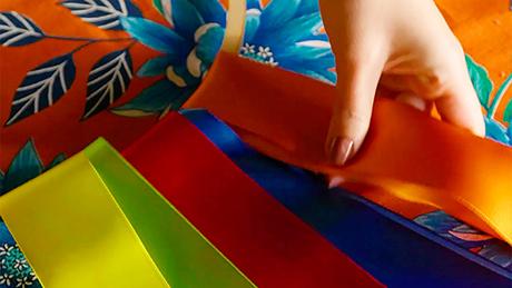 Fitas coloridas são posicionadas em argola feita de bastidor de tecido, em atividade de decoração artesanal de festa junina