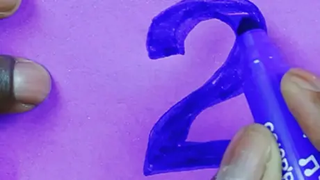 Com uma canetinha azul, uma pessoa escreve um número sobre um papel para brincadeira de adivinhação em festa junina