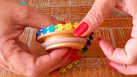 Adornos florais de festa junina são colados sobre a tampa de madeira de um potinho de vidro para criar decoração customizada