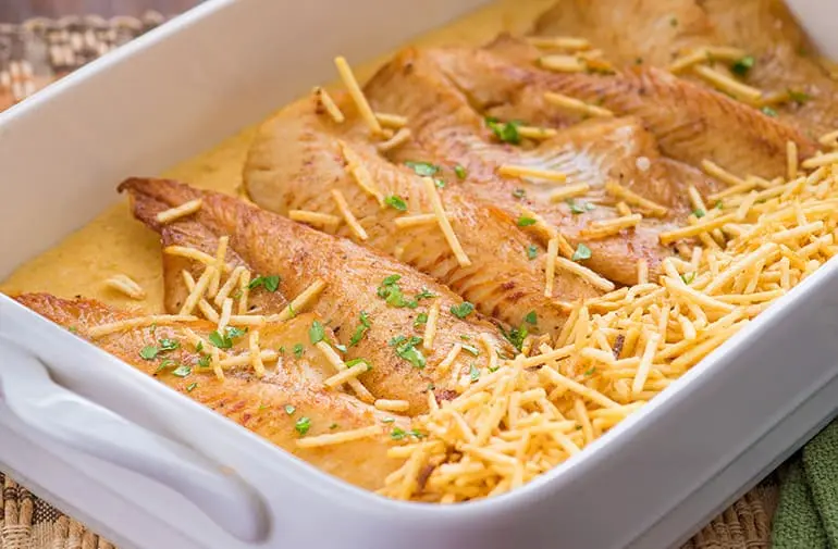 Travessa com filés de merluza fritos, cobertos com creme de grão de bico e finalizados com batata palha