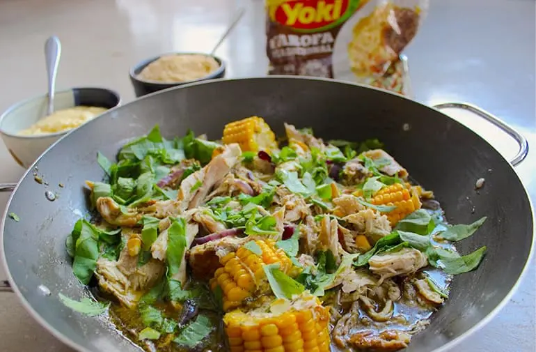 Panela grande de frango desfiado ensopado com angu mineiro e espigas de milho, com acompanhamento de farofa Yoki