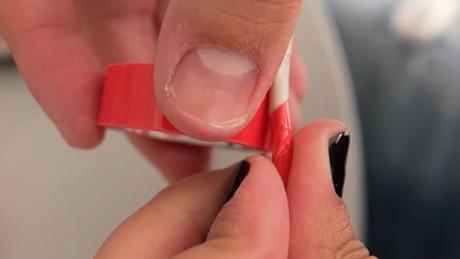 Pessoa passa fita vermelha sobre argola de arame para decorar atividade de festa junina