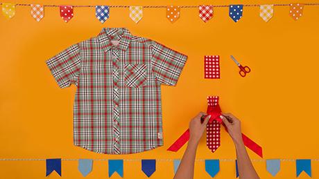 Mãos dão um nó sobre pedaço de tecido para criar uma gravata em traje típico de festa junina para meninos