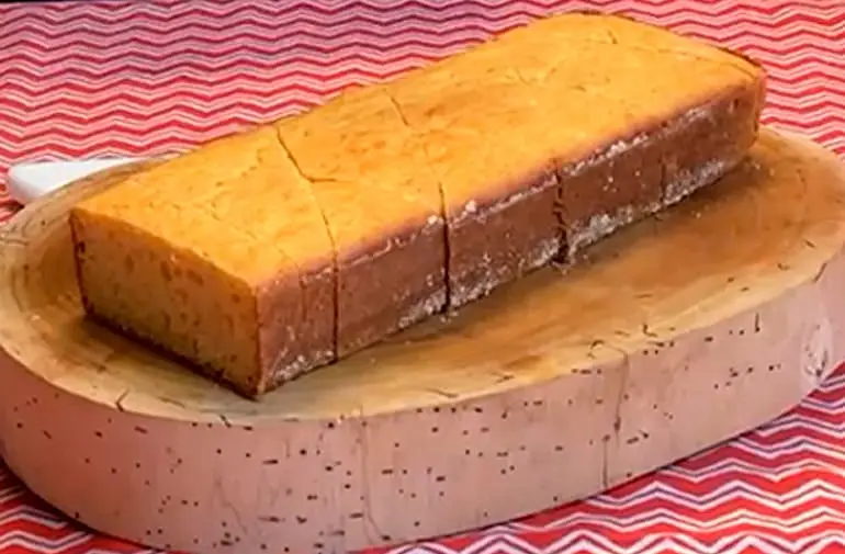 Receita de pão de fubá caseiro cortado em fatias, servido sobre tábua de madeira em festa junina