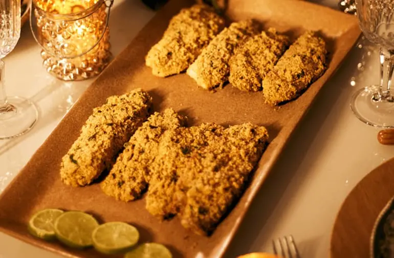 Filés de peixe assado ao forno com crosta crocante de farofa de ervas servido em bandeja com rodelas de limão