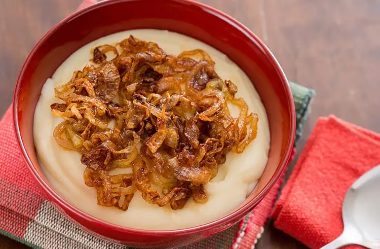 Purê de batata Yoki com cebola caramelizada dourada, em tigela vermelha, consistência cremosa