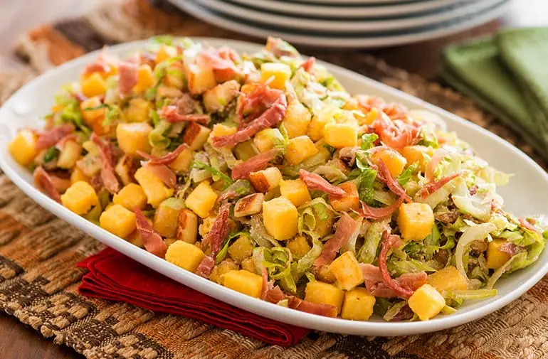 Salada de polenta pronta, presunto parma, ricota e vegetais, em mesa com jogo americano de vime