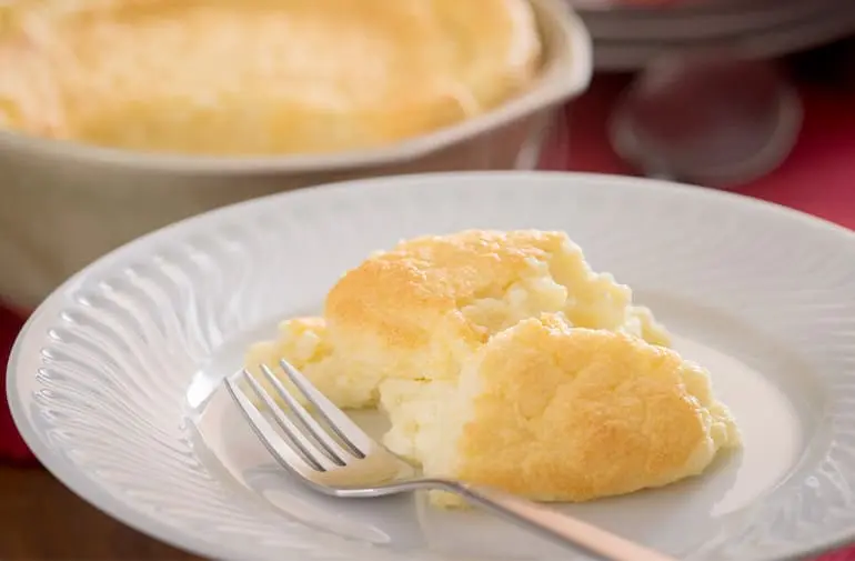 Porção cremosa de suflê de batata com molho branco em prato de porcelana branco